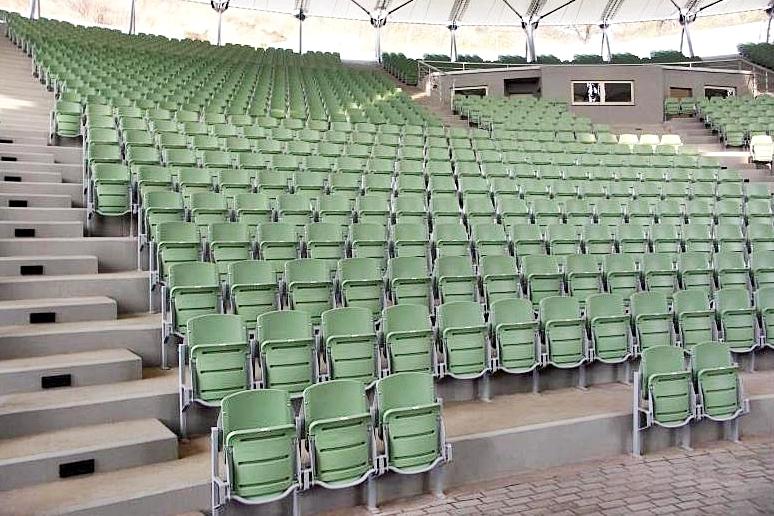 Krzeseka stadionowe zielone z podnoszonym grawitacyjnie siedziskiem na metalowej konstrukcji stojącej 