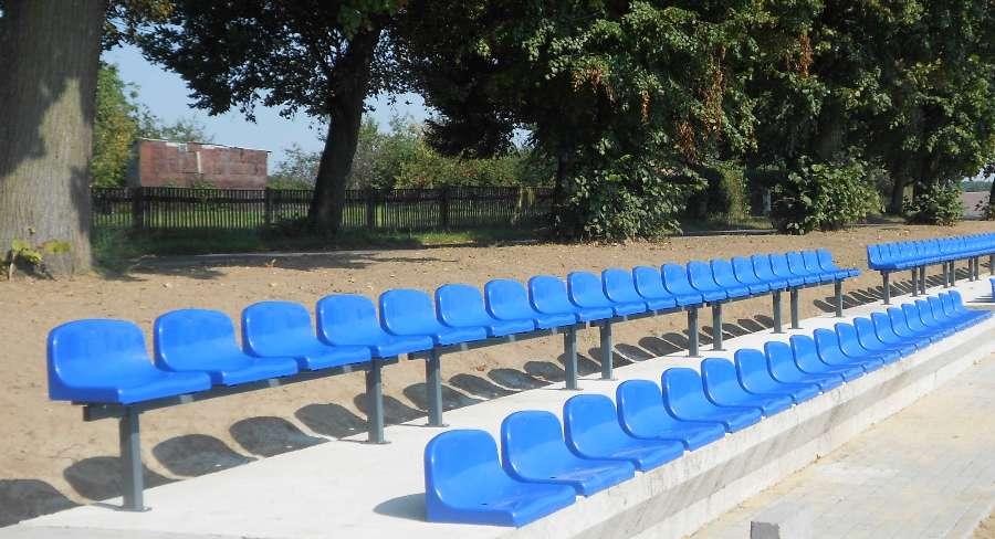 Krzesła stadionowe na stojącej metalowej konstrukcji na trybunie wiejskiego boiska piłkarskiego sportowego 
