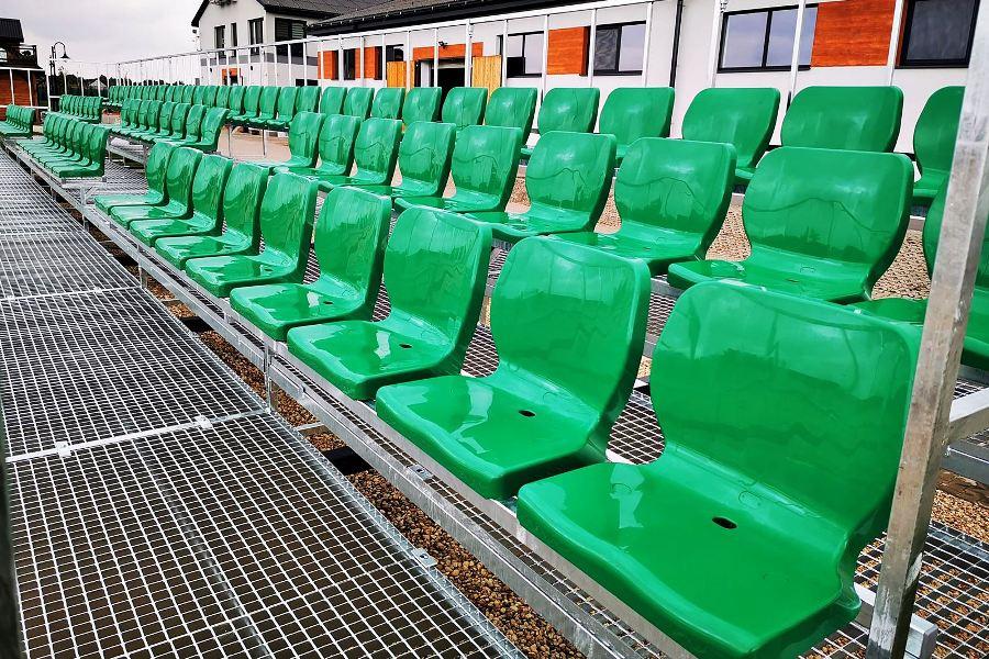 nowoczesne i ergonomiczne zielone fotele stadionowe zamocowane na zewnętrznej trybunie sportowej 