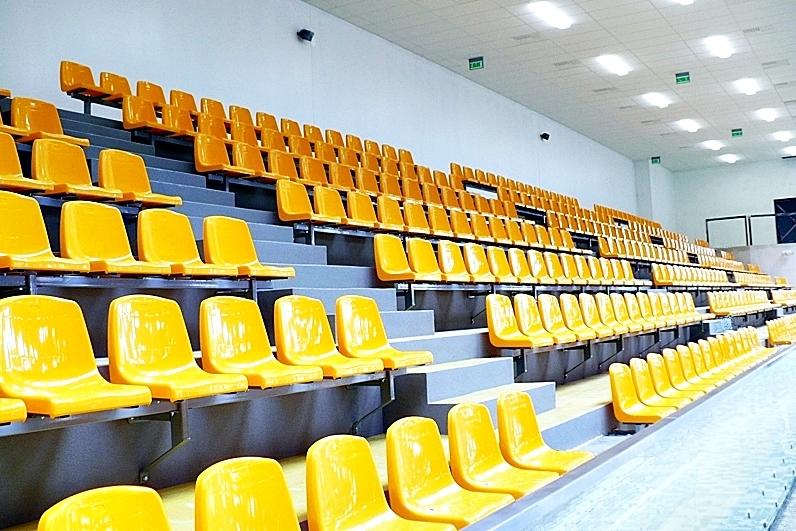 żółte siedziska stadionowe z wysokim oparciem 36 cm na stopniach trybuny sportowej w hali widowiskowej 